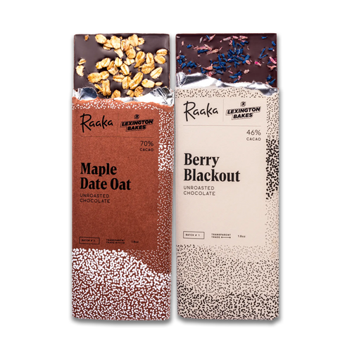 Two packaged chocolate bars from Raaka and Lexington Bakes standing side by side on a white background. The left bar is Maple Date Oat and the right is Berry Blackout.